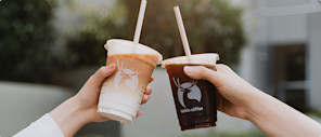Two hands touching Luckin Coffee cups full of different coffee drinks.